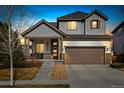 Dusk view of a charming two-story home with a well-manicured lawn and inviting front porch at 10788 Ventura St, Commerce City, CO 80022