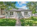 Charming single-story home featuring a well-kept lawn, grey paint and easy access to the front door via a sidewalk at 1177 Wabash St, Denver, CO 80220