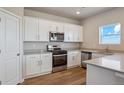 Modern kitchen with white cabinetry, stainless steel appliances, and hardwood floors at 48260 Shetland Dr, Bennett, CO 80102