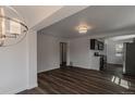 Living room featuring dark hardwood flooring, white walls, recessed lighting, and access to the kitchen at 3360 Magnolia St, Denver, CO 80207