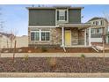 Inviting two-story home with a covered porch, stone accents, a yellow front door, and well-maintained landscaping at 4138 N Quatar Ct, Aurora, CO 80019
