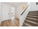 Inviting entryway with wood floors, a white front door, and staircase leading to the upper level of the home at 190 Lark Sparrow Way, Bennett, CO 80102