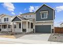 Two-story home featuring a charming front porch, gray siding, well-manicured landscaping, and an attached two-car garage at 190 Lark Sparrow Way, Bennett, CO 80102
