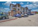 Apartment building with stone and siding facade, balconies, and ample parking on a sunny day at 1401 W 85Th Ave # F201, Federal Heights, CO 80260