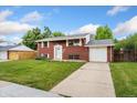 Charming two-story red brick home with a well-manicured lawn and driveway at 6721 Quay Ct, Arvada, CO 80003
