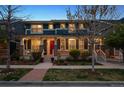 Inviting two-story home with a cozy front porch, red door, and well-maintained landscaping at 9446 E 51St Dr, Denver, CO 80238