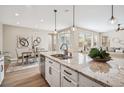 Spacious kitchen island with granite countertops, stainless steel sink, and an open view to the living and dining areas at 9446 E 51St Dr, Denver, CO 80238