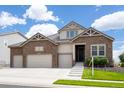 Two-story house with stone and beige siding, three-car garage, and landscaped yard at 15994 La Plata Peak Pl, Broomfield, CO 80023