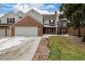 Charming two-story home featuring a brick facade, attached garage, and well-maintained lawn with mature trees at 7501 S Ivanhoe Cir, Centennial, CO 80112