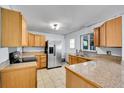 Functional kitchen featuring stainless steel appliances, wood cabinetry, granite countertops, and tile flooring at 414 S Nelson S St, Lakewood, CO 80226