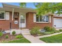 Inviting front porch with brick facade, concrete steps, and manicured landscaping adds curb appeal at 7901 E Kenyon Dr, Denver, CO 80237