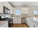 Well-equipped kitchen with stainless steel appliances, white cabinets, quartz countertops, and a view from the window at 48290 Shetland Dr, Bennett, CO 80102