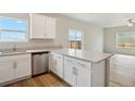 Kitchen featuring stainless steel dishwasher, a large island with white cabinets and hard surface countertops at 48290 Shetland Dr, Bennett, CO 80102