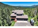Aerial view of stunning blue home nestled amongst lush greenery with a large garage at 30889 Manitoba Dr, Evergreen, CO 80439