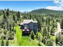 Lovely backyard with a large deck, lush greenery, and scenic views of the mountains at 30889 Manitoba Dr, Evergreen, CO 80439