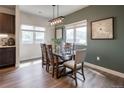 A dining room with wood table, six chairs, modern lighting fixture and view of adjacent buildings through the windows at 4184 Kalamath St, Denver, CO 80211