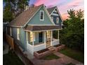 Charming home featuring a covered front porch, brick garden beds, and walkway, framed by mature trees at dusk at 2527 W Dunkeld Pl, Denver, CO 80211