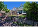 Charming blue home featuring a well-manicured front yard and black iron fence at 2527 W Dunkeld Pl, Denver, CO 80211