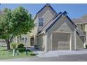 Image of a charming two-story home featuring a two-car garage, with green lawn and mature tree at 10359 W Fair Ave # F, Littleton, CO 80127