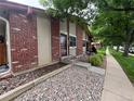 Townhome front featuring well-kept landscaping, a secure screen door, and decorative rock at 7020 W Portland Ave, Littleton, CO 80128