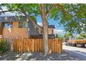 View of the back of the townhome with a mature tree providing shade and a wooden privacy fence at 7995 E Mississippi Ave # F23, Denver, CO 80247
