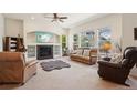 Bright living room featuring a ceiling fan, fireplace, large windows and comfortable leather furniture at 4553 Red Deer Trl, Broomfield, CO 80020