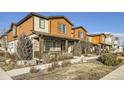 View of well-maintained townhomes showcasing stone accents and neutral color schemes, with covered porches at 21613 E 59Th Pl, Aurora, CO 80019