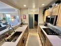 Galley kitchen with updated appliances, mosaic tile backsplash, and an open view to the living area at 300 W 11Th Ave # 10D, Denver, CO 80204