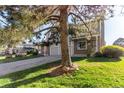Home with an attached garage and a large tree in the front yard at 1745 S Kline Way, Lakewood, CO 80232