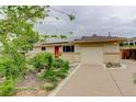Single-story home with a red front door, solar panels, one car garage, and beautiful landscaping at 9743 W 67Th Pl, Arvada, CO 80004