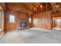 Spacious living room featuring a brick fireplace, wood paneling, and high ceilings with exposed beams at 8409 S Otis St, Littleton, CO 80128