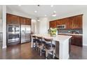 Modern kitchen with dark wood cabinets, stainless steel appliances, a marble island, and stylish bar stools at 26642 E Peakview Pl, Aurora, CO 80016