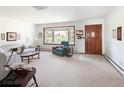 Bright living room featuring a large bay window, neutral carpet and wood door at 2900 S Golden Way, Denver, CO 80227