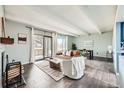 Cozy living room featuring a fireplace, exposed beams, hardwood floors, and access to a private balcony at 2525 S Dayton Way # 1003, Denver, CO 80231