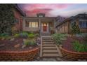 Charming brick home featuring a cozy front porch, brick garden bed, and inviting red front door at sunset at 3259 Lowell Blvd, Denver, CO 80211