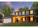 Inviting two-story home featuring a cozy covered front porch, a well-manicured lawn, and warm lighting at 504 E Otero Ct, Littleton, CO 80122