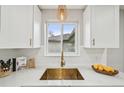 Bright kitchen features white cabinetry, subway tile backsplash, and modern gold fixtures at 3285 N Monaco Pkwy, Denver, CO 80207