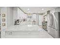 Bright kitchen featuring marble countertops, stainless steel appliances, an island, and modern white cabinetry at 3285 N Monaco Pkwy, Denver, CO 80207