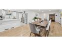 Kitchen with white cabinets, marble countertops, stainless appliances open to dining room with wood table at 3285 N Monaco Pkwy, Denver, CO 80207