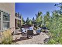 A circular stone patio with comfortable seating overlooks a lush, beautifully landscaped yard at 10553 Fairhurst Way, Highlands Ranch, CO 80126