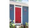 Close-up of a bright red front door with vintage outdoor lighting sconces on a blue-sided home at 12175 Birch St, Thornton, CO 80241