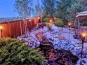 A tranquil backyard features a stone water feature, tiki torches, and mature landscaping, creating a serene outdoor retreat at 11302 Mesa Verde Pl, Parker, CO 80138