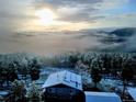 Panoramic aerial view of a snow-dusted house with solar panels amidst a misty mountain landscape at 8 Sioux Trl, Evergreen, CO 80439