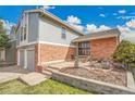Attractive home with brick facade, manicured front garden bed, and gray painted trim under bright, cloudy sky at 11488 E Amherst S Cir, Aurora, CO 80014