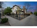 Attractive corner lot featuring a well-manicured lawn, landscaped garden beds, mature trees, and black metal fencing at 3366 Willow St, Denver, CO 80238