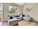 Bright living room featuring a plush sectional sofa, hardwood floors, and a large window showcasing outdoor greenery at 1099 S Walden Way # 205, Aurora, CO 80017