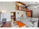 Inviting living room featuring high ceilings, wood floors, a large sectional, and a view of the upper floor at 10525 Hobbit Ln, Westminster, CO 80031