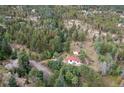 Charming home nestled among trees with a red roof and a sprawling, wooded landscape at 11827 Brook Rd, Golden, CO 80403