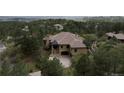 A beautiful house set back in the trees, with a driveway leading up to the home and garage and stone entryway at 214 Equinox Dr, Castle Rock, CO 80108