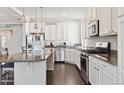 Modern kitchen featuring stainless steel appliances, white cabinetry, granite countertops, and stylish pendant lighting at 19802 E 54Th Ave, Denver, CO 80249